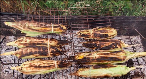 Запечённые кукурузные початки с листьями на решётке мангала